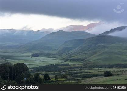 First rays of sunlight of the day shine through the mist on the mountain Drakensberg South Africa