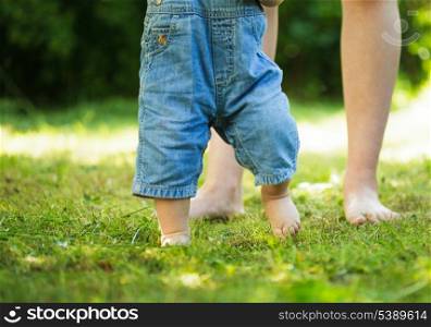 First steps of baby from mother on grass