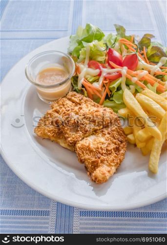 fish and chips. Deep fried fish steak served with french fries and fresh vegetables on white plate