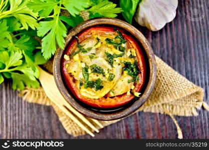 Fish baked in tomato in Zandvoort in clay bowl on a napkin of burlap, parsley on a dark wooden board on top