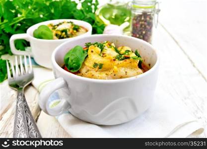 Fish baked in tomato in Zandvoort in two white bowls on a napkin, parsley and fork on the background of wooden boards