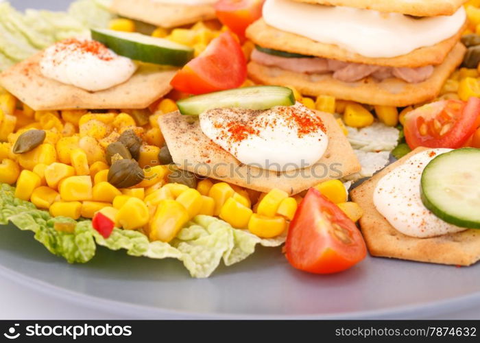 Fish cream in pastries, sweet corn, cherry tomato and lettuce on gray plate.