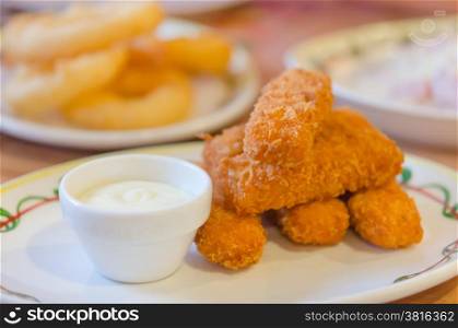 fish fingers . fresh fish fingers and white sauce on dish