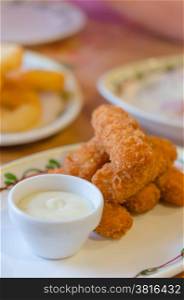 fish fingers . fresh fish fingers and white sauce on dish