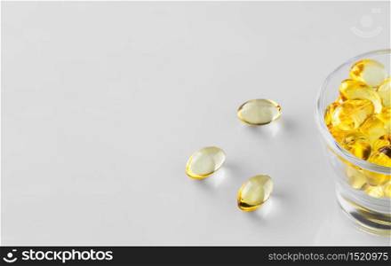 Fish oil capsules (omega-3) in a glass bowl. Close-up, white background with copy space for the recipe. healthy food additives.