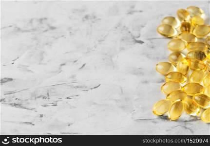 Fish oil capsules (omega-3) on a gray marble background. Close-up with shallow depth of field with copy space for the recipe. Useful food supplements.