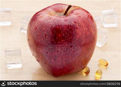 Fish oil pills and red apple on wooden background. Fish oil pills and fresh red apple on wooden background