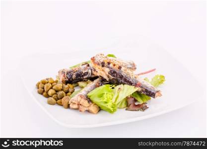 Fish, peppers, lettuce and capers on white plate.