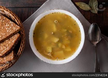 Fish soup in a plate on a brown background. Diet fish soup and cereal bread on the table, flat lay. Fish soup in a plate on a brown background