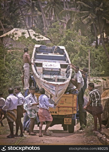 Fisher men are loading a fishing boat on a lorry at Vizhinjam harbour, Trivandrum, Kerala, India