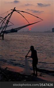 Fisherman and Kochi chinese fishnets on sunset. Fort Kochin, Kochi, Kerala, India