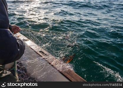 Fisherman bringing back net in a boat in Brittany