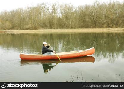 Fisherman canoeing on the pond in winter