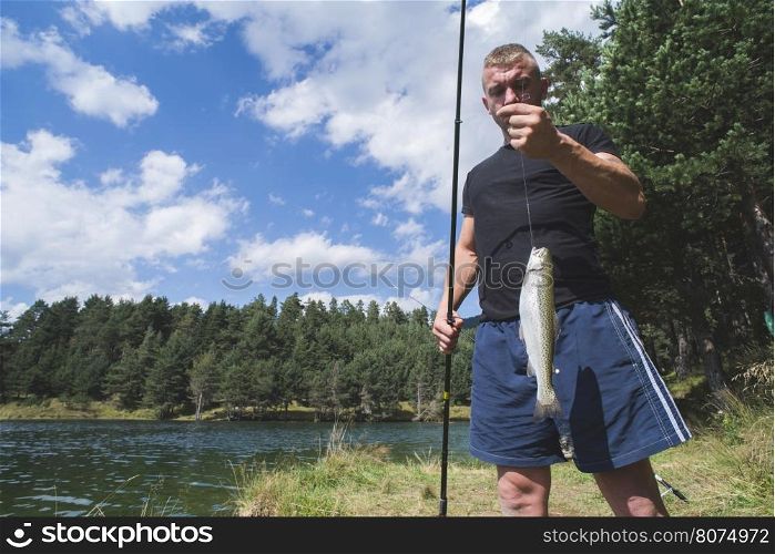 Fisherman caught a fish in mountain dam. Bulgaria