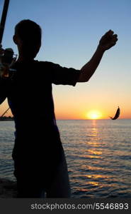 Fisherman fishes on the lake. Silhouette at sunset