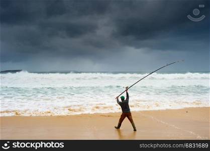 Fisherman fishing on the beach in a stormy weather
