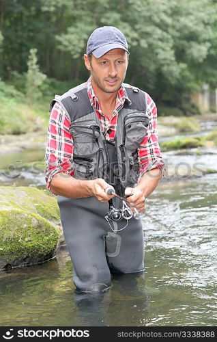 Fisherman in river with fishing rod