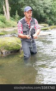 Fisherman in river with fishing rod