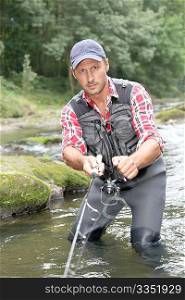 Fisherman in river with fishing rod