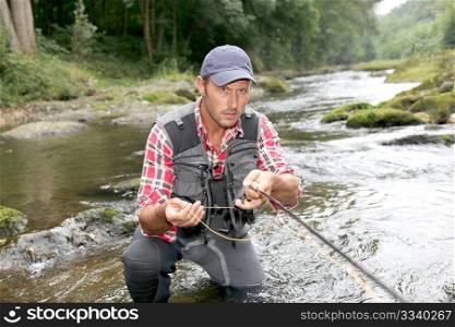 Fisherman in river with fly fishing rod