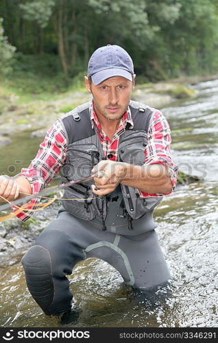 Fisherman in river with fly fishing rod