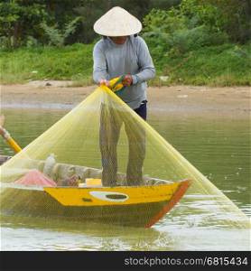 Fisherman is fishing with a large net in a river in Vietnam (Hoi An)
