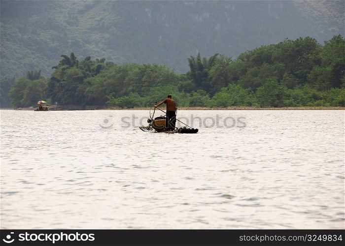 Fisherman on a bamboo raft in a river, XingPing, Yangshuo, Guangxi Province, China