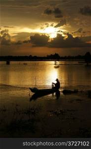 Fisherman on rowboat do fishing on river in flood season at sunrise