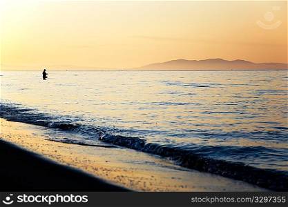 Fisherman silhouette at sunrise, Tuscany, Italy