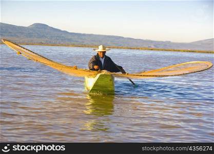 Fisherman with butterfly fishing net in a lake, Janitzio Island, Lake Patzcuaro, Patzcuaro, Michoacan State, Mexico