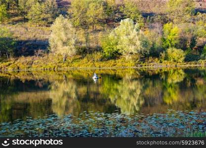 Fishermen in a boat on a lake in the countryside in autumn