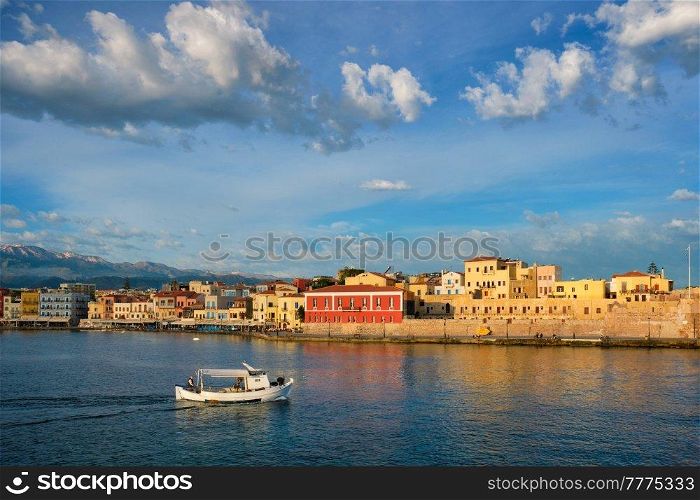 Fishing boat going to sea in picturesque old port of Chania is one of landmarks and tourist destinations of Crete island in the morning. Chania, Crete, Greece. Boat in picturesque old port of Chania, Crete island. Greece