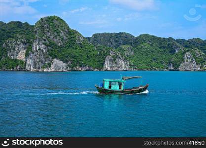 Fishing boat in Halong Bay, Vietnam, Southeast Asia. UNESCO World Heritage Site. Beautiful scenery with sea and mountain at Ha Long Bay, Vietnam. Most popular landmark, tourist destination of Vietnam.. Fishing boat in Halong Bay, Vietnam Southeast Asia