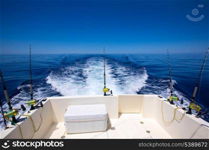 Fishing boat stern deck with trolling fishing rods and reels in blue ocean sea