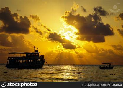 Fishing boat trawler and fisherman on the water ocean and dramatic clouds sky at sunrise / fishing boat sea at dawn silhouette sunset