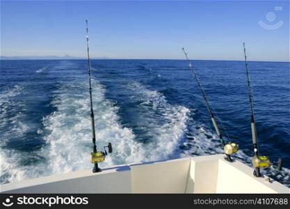 Fishing boat with three big game rods an reels, ocean blue sea