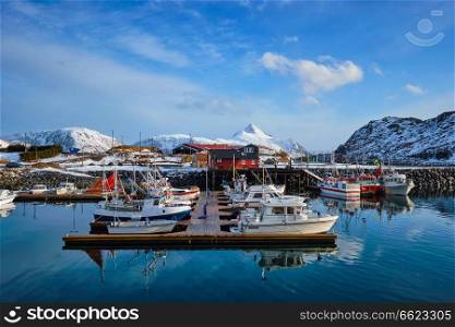 Fishing boats and yachts on pier in Norwegian fjord in village on Lofoten islands in winter, Norway. Fishing boats and yachts on pier in Norway