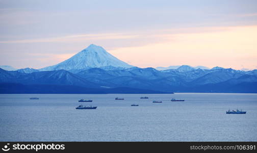 fishing boats in the Bay with the volcano in autumn on Kamchatka