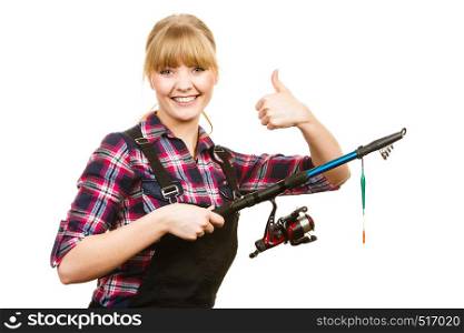 Fishing concept. Attractive woman in dungarees,pink check shirt holding rod showing thumb up. Isolated background. Woman with fishing rod showing thumb up