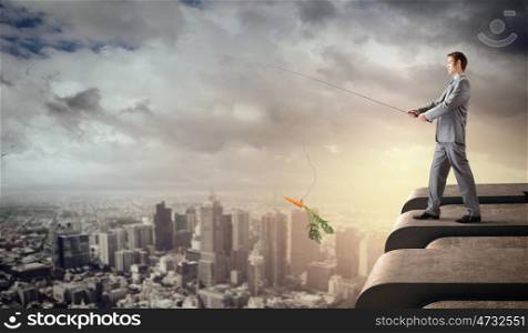 Fishing concept. Businessman standing on top of building and fishing with rod