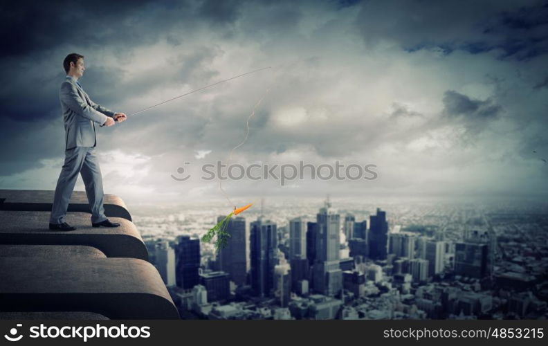 Fishing concept. Businessman standing on top of building and fishing with rod