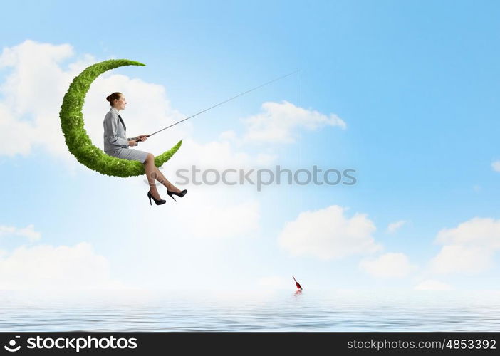 Fishing concept. Businesswoman fishing with rod on green moon