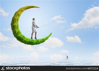 Fishing concept. Businesswoman fishing with rod on green moon