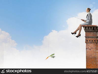 Fishing concept. Businesswoman fishing with rod on top of building