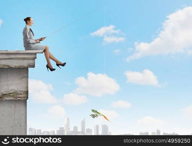 Fishing concept. Businesswoman fishing with rod on top of building