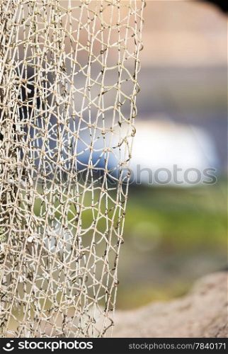 Fishing equipment. Closeup of old net. White fishnet on shore outdoor.