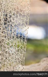 Fishing equipment. Closeup of old net. White fishnet on shore outdoor.