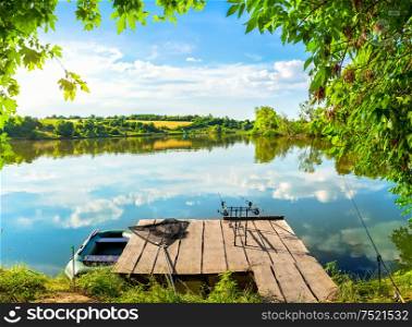 Fishing equipment on wooden pier and calm river in the morning