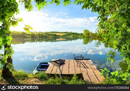 Fishing equipment on wooden pier and calm river in the morning. Wooden pier and pond