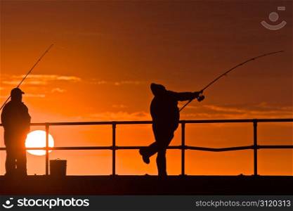 Fishing for Dinner. Men fishing, silhouettes with sunrise